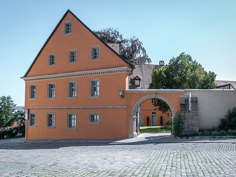 Historisches Gebäude mit orangefarbener Fassade, Torbogen und Kopfsteinpflaster in Bamberg.