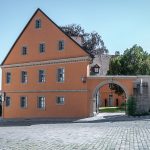 Historisches Gebäude mit orangefarbener Fassade, Torbogen und Kopfsteinpflaster in Bamberg.