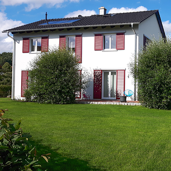 Freistehendes Einfamilienhaus mit blauer Dachkonstruktion und großem Rasen