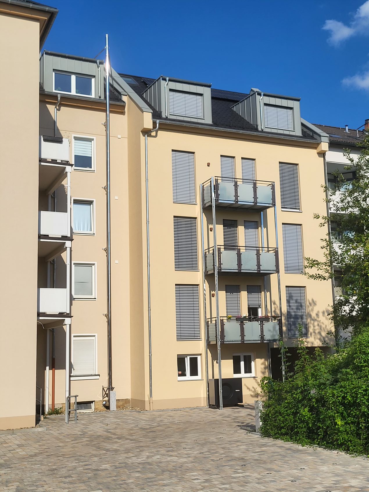 Ein vierstöckiges, gelb-beiges Wohnhaus mit mehreren Balkonen und modernen Fenstern.
